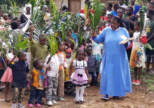 Sister Jane walking with children and families with palms
